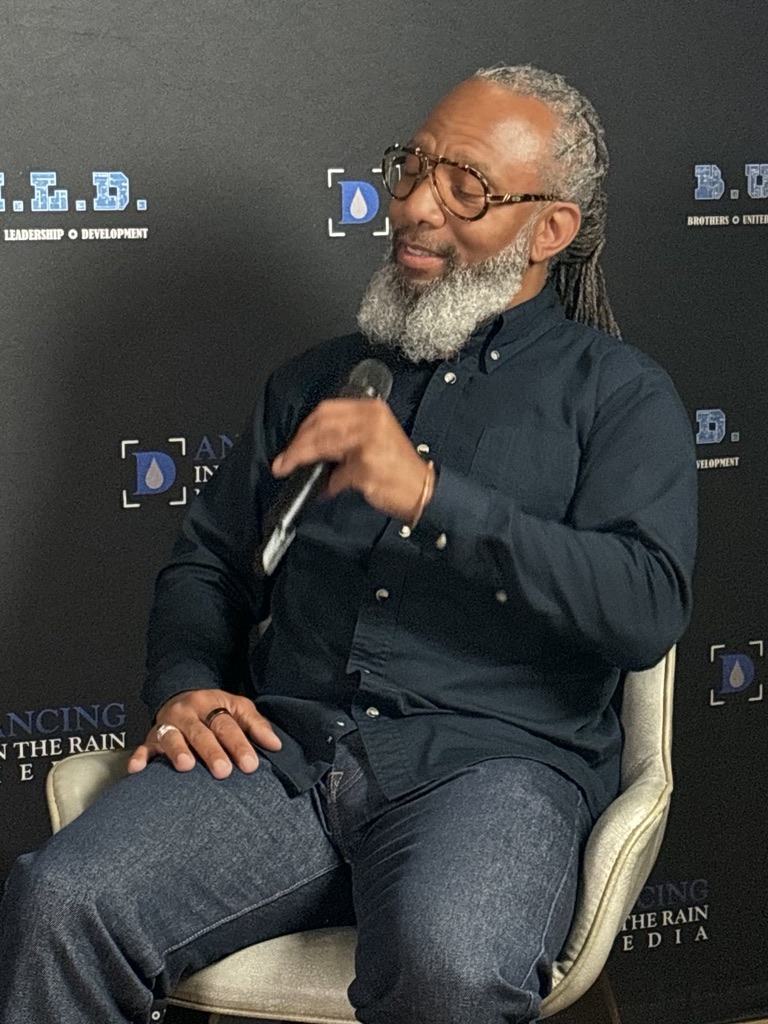 Heru TchaasAmen speaking with a microphone at a B.U.L.D. leadership event