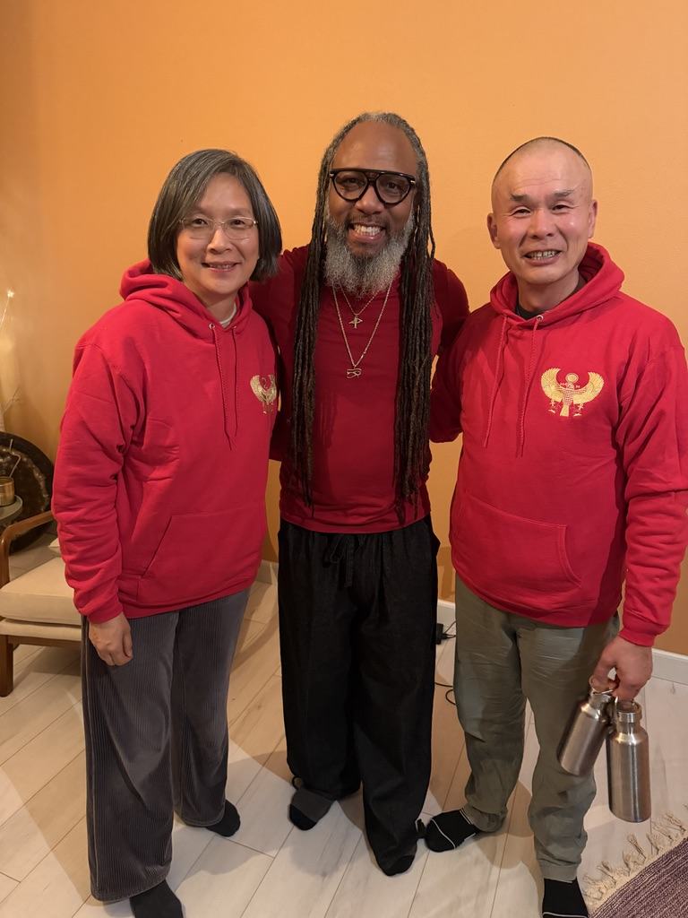 Heru TchaasAmen with two community members wearing branded Heru Heals hoodies