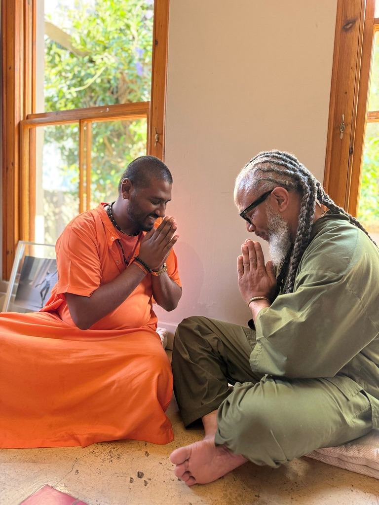 Heru TchaasAmen sharing a namaste gesture with a visiting monk