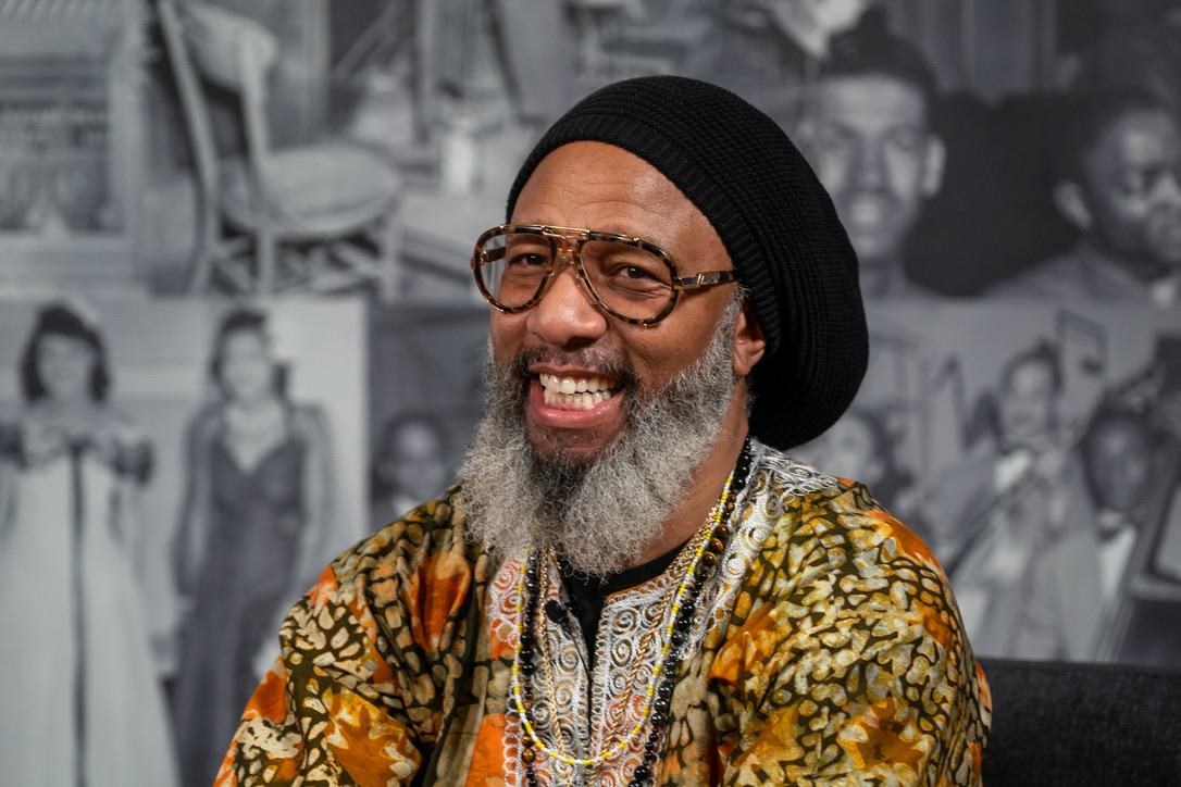 Heru TchaasAmen smiling warmly at the Legacy exhibit