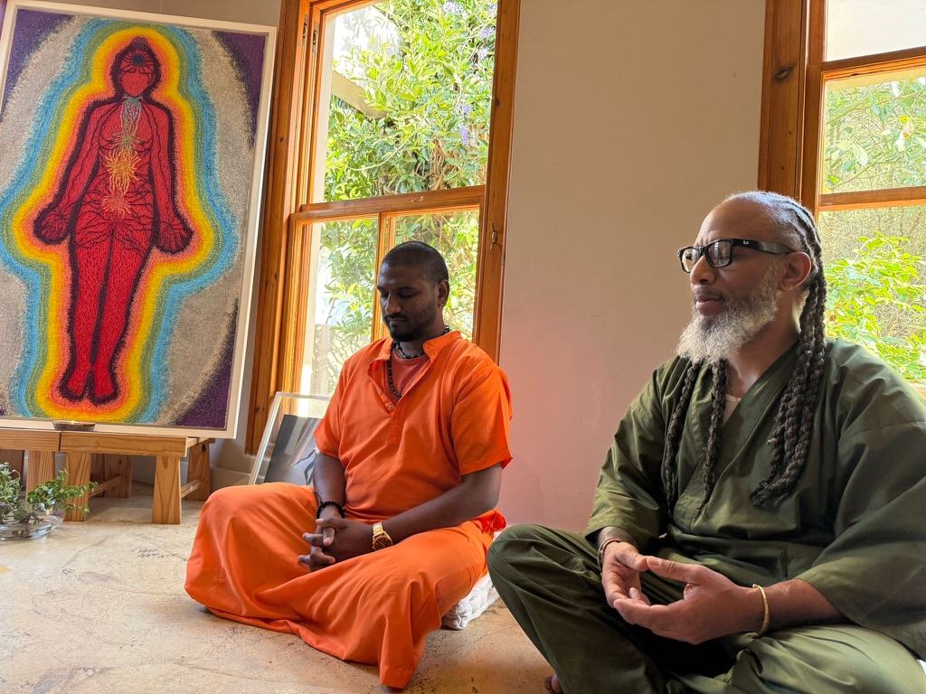 Heru TchaasAmen meditating beside an energy body painting